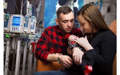 Young couple hold baby in their arms