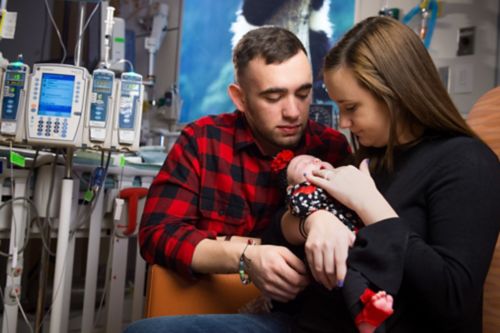 Parents holding infant in a hospital setting