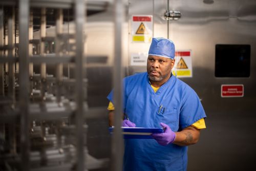 Man in scrubs by shelves