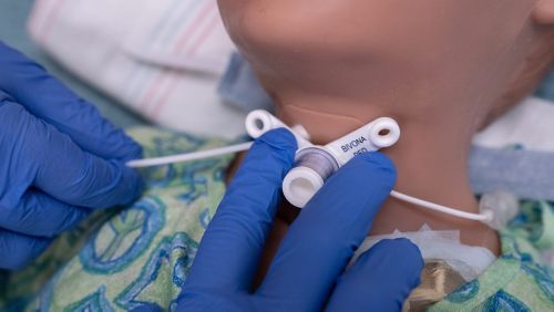Nurse demonstrates where the trach stoma flanges are.