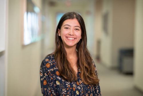 Student wearing a floral shirt smiles at camera.