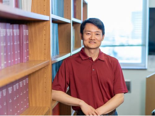 Photo of Haitao Pan standing in front of a bookcase