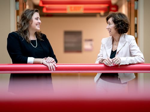 two women standing at a railing talking