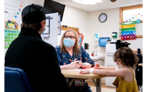 Parent and child speak with counselor in school classroom setting