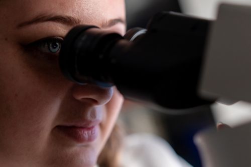 woman looking into microscope