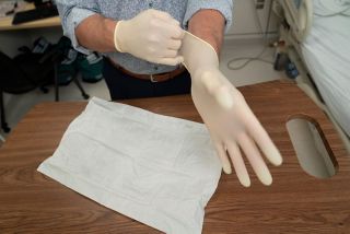 Pulling on second sterile glove and only touch the outside of the glove