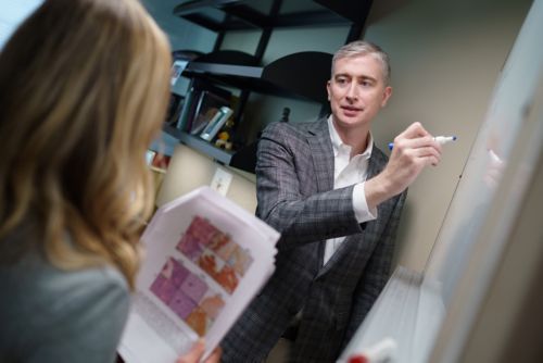 Man at a whiteboard with woman watching