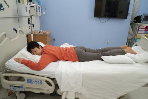 Woman lying on stomach on bed.