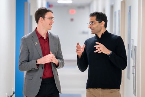 Christian Meyer and Anang Shelat walking in a hallway