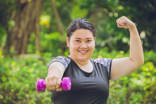 Teen holding a weight in one arm and flexing arm muscle in other arm