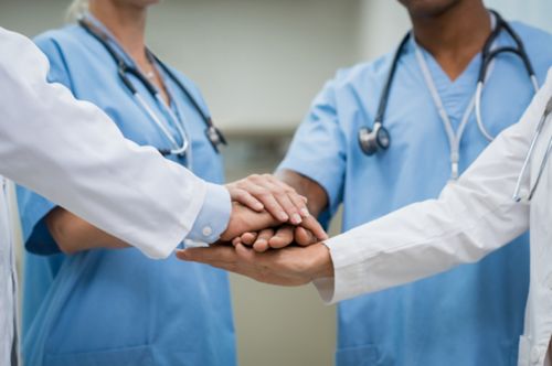 closeup of doctors in group with hands in circle