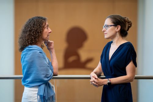 Two women talking in front of a railing