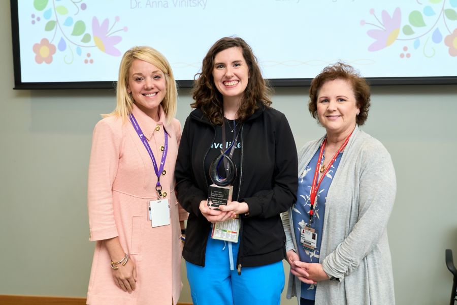 Group photo of three women with one holding award