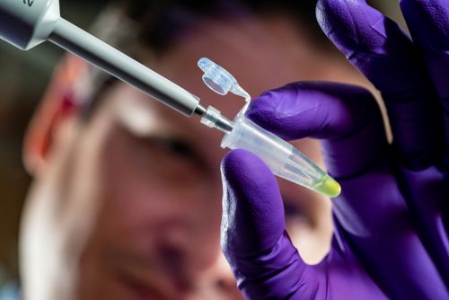 Man injecting serum into a small vial