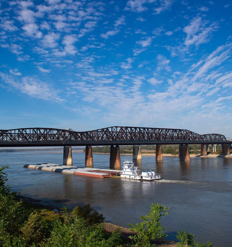 Photo of tug pushing barge down the Mississippi River at the Memphis & Arkansas Bridge