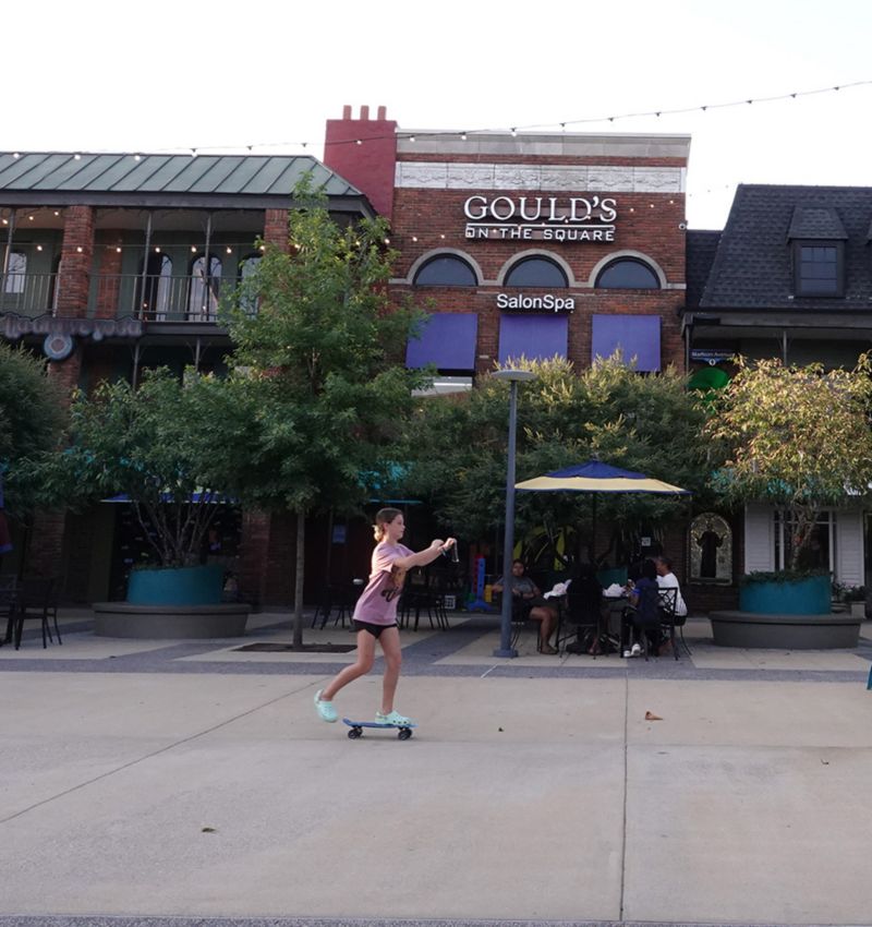photo of girl riding skateboard in courtyard behind Overton Square