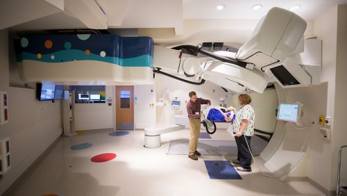 photo of child getting proton therapy treatment w/doctor and nurse attending