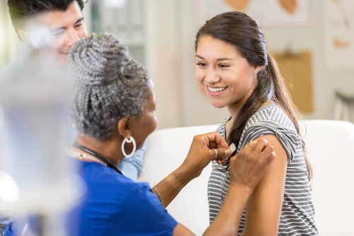 photo of girl getting bandaid on arm after receiving vaccination