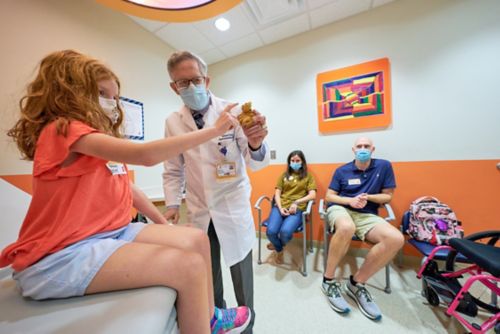 photo of doctor and patient interacting as family looks on.