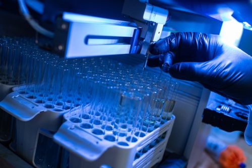 image of test tubes in lab with gloved hand holding one