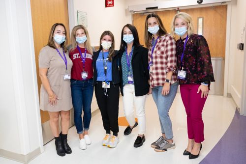 group of women in surgical masks standing in hallway 