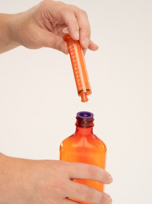 Person holding Enfit syringe and bottle