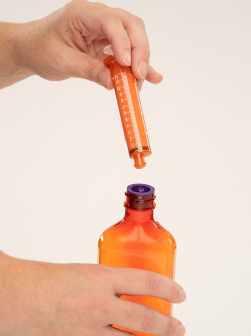 Person holding Enfit syringe and bottle
