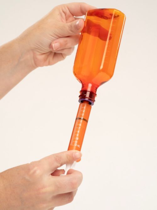 Person holding bottle upside down with syringe 