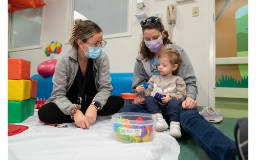 Two women in play area with one holding a small child