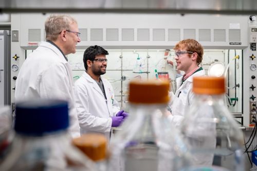 Three men talking in a lab
