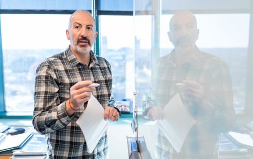 Image of man in flannel shirt reflected in whiteboard