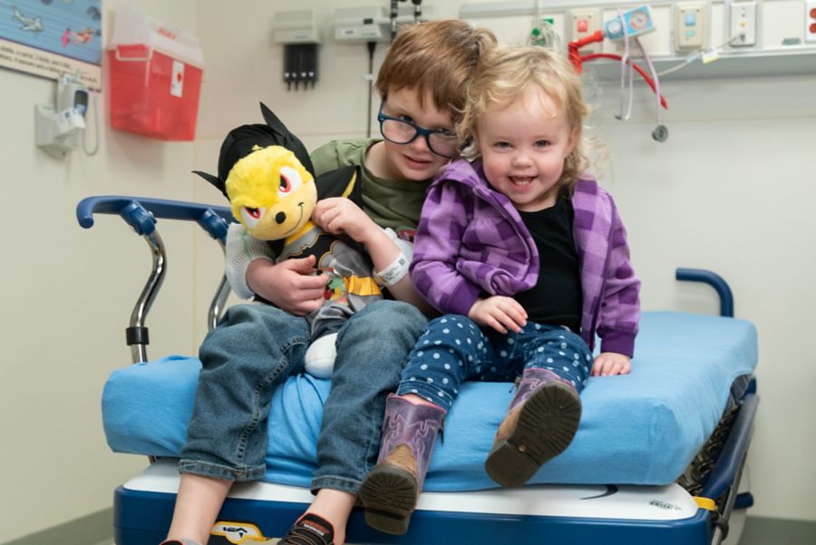 Two small children sitting on hospital bed