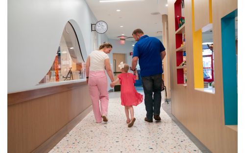 Parents walk with daughter in hallway of Family Commons