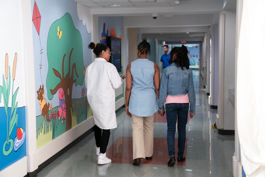 patients walking down the hallway of a hospital with a doctor