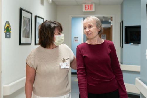 A patient walking with a care team member