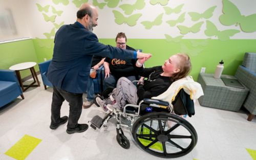 Man in dark site greets girl in wheelchair
