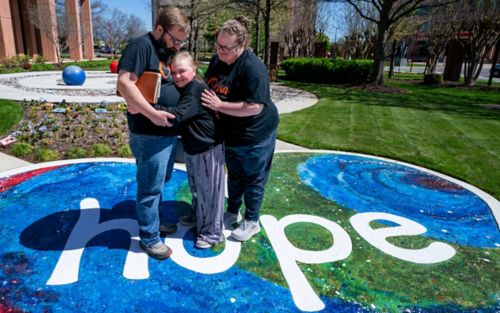 Parents and child standing on painted heart that says hope