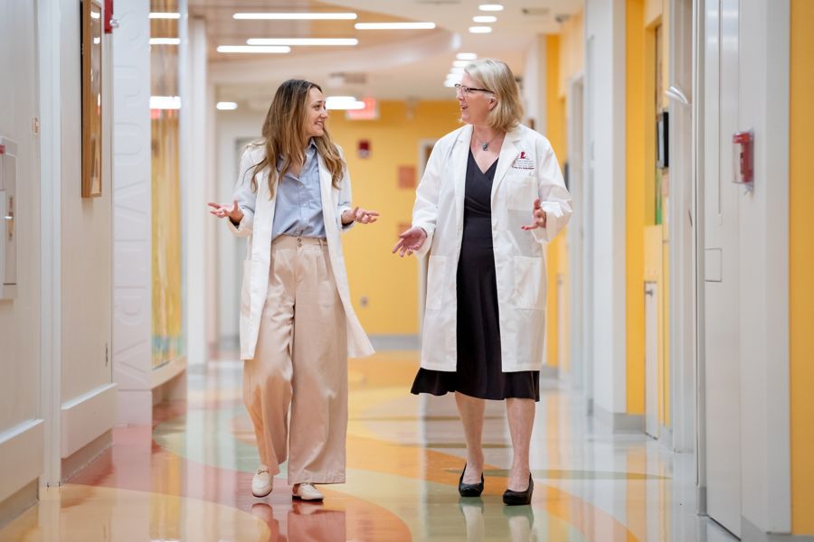 Two women doctors talking and walking in hallway