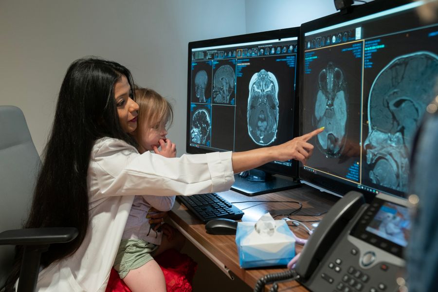 Doctor holds child while pointing to brain diagnostic image
