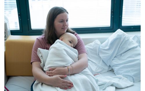 Mother holding baby wrapped in blanket in hospital room