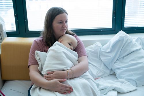 Mother holding baby wrapped in a blanket in hospital room