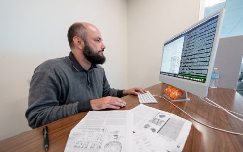 two women in lab coats looking at image on a giant computer monitor