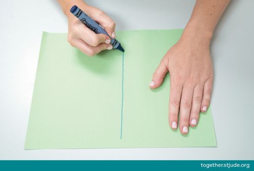 Person drawing vertical line on construction paper