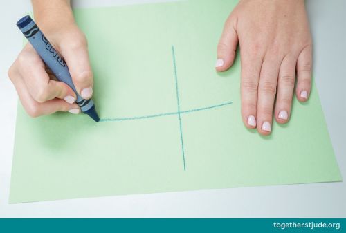 Person drawing cross on construction paper