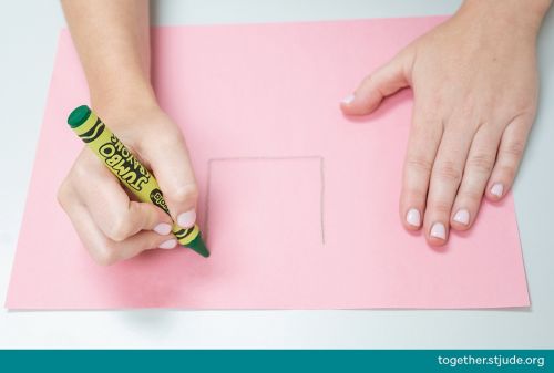 Person drawing a square on construction paper