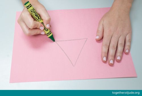 Person drawing a triangle on construction paper