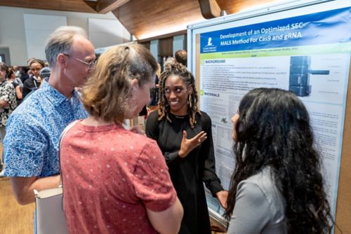 Group of people looking at a poster while one person explains it.