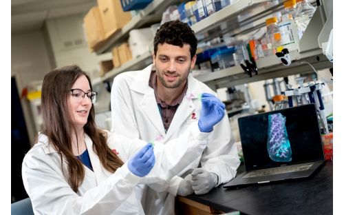 Two people in white coats examining a slide.