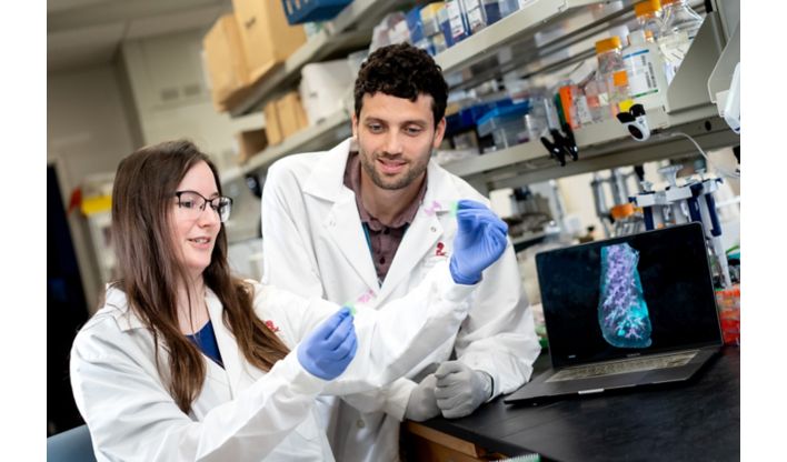 Two people in white coats examining a slide.