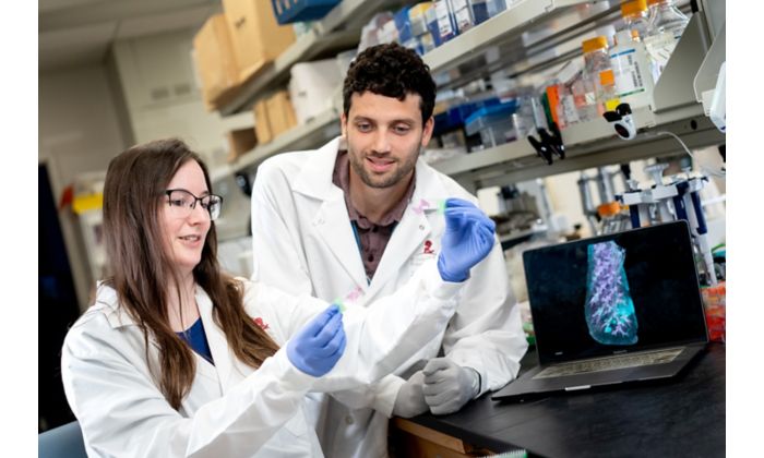 Two people in white coats examining a slide.